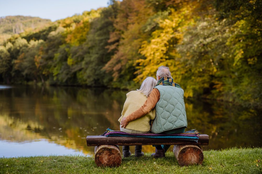 Senior,Couple,In,Love,Sitting,Together,On,Bench,Looking,At